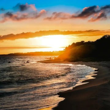 Beach sunset with golden sky and calm ocean waves