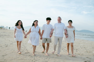 Family walking hand-in-hand on a sandy beach.