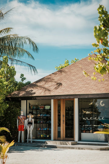 Mannequins in swimwear outside a tropical island shop.