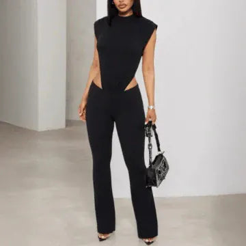 Woman wearing a black sleeveless jumpsuit with cut-out design, standing against a plain background.