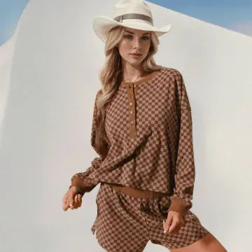 Woman wearing a brown checkered outfit with a white hat against a white background